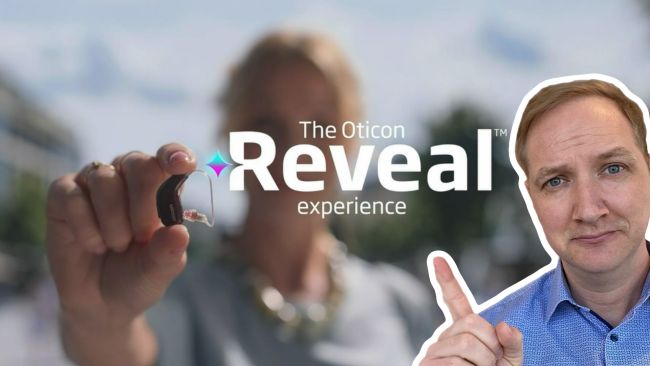 Maximilian Bauer zeigt mit dem Finger auf Das neue Hörgerät von Oticon. das Reveal.