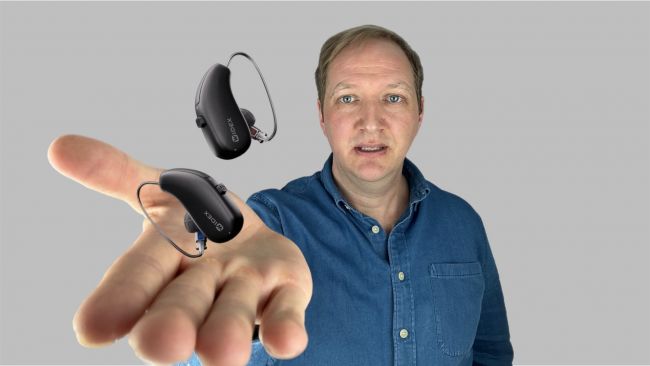 Widex Allure schweben in der Hand des Audiologen Maximilian Bauer. Hintergrund grau.